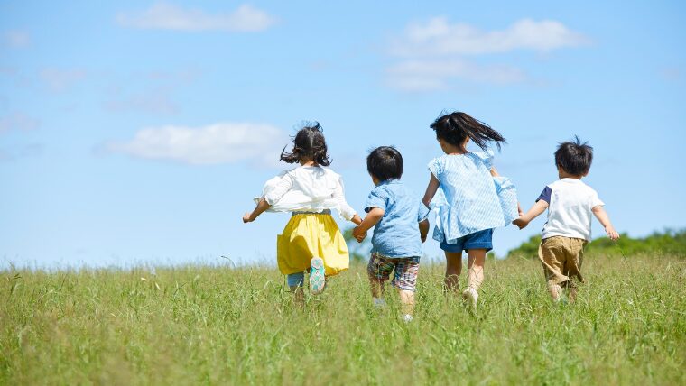 子ども4人が草原を走る後ろ姿