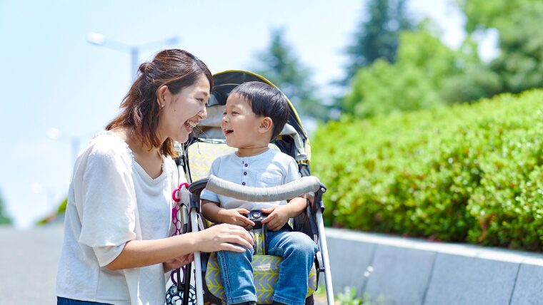 ベビーカーに乗る子どもと、目線を合わせて話す母親