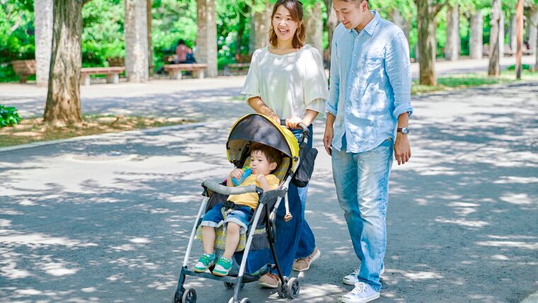 子どもを乗せたベビーカーを押す母親と、一緒に歩く父親