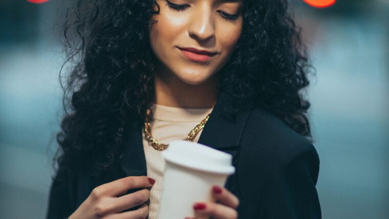 テイクアウトしたコーヒーカップを手に持つ女性